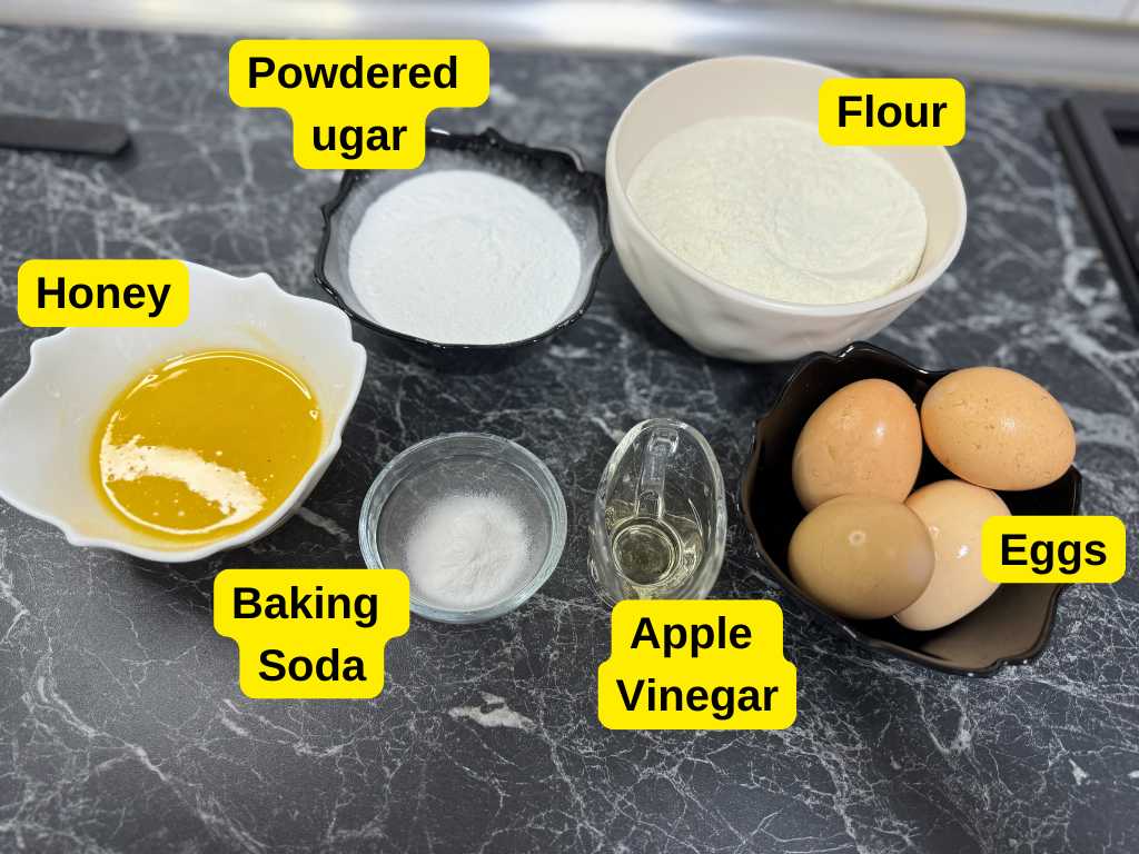 Ingredients for honey bun cake: flour, powdered sugar, eggs, honey, baking soda, and apple vinegar
