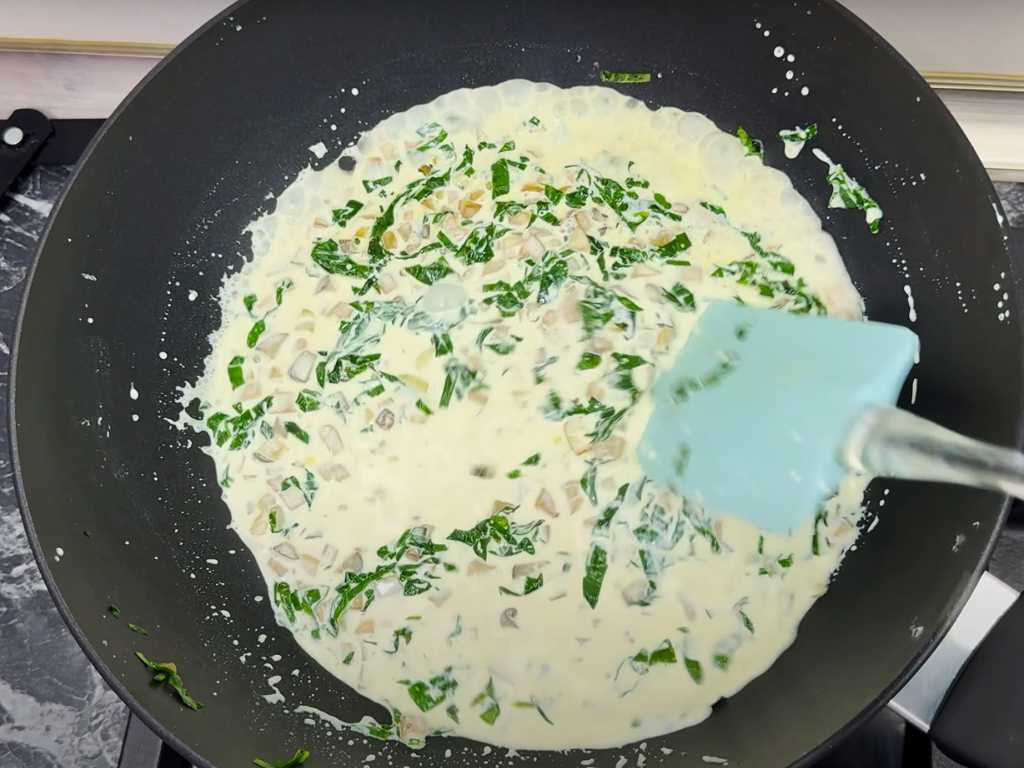 Cooking creamy spinach and mushroom filling in a pan for shrimp stuffed mushrooms