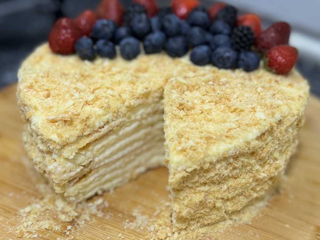 Whole Napoleon Cake topped with fresh berries, showing layers of flaky puff pastry and creamy custard with a slice cut out.