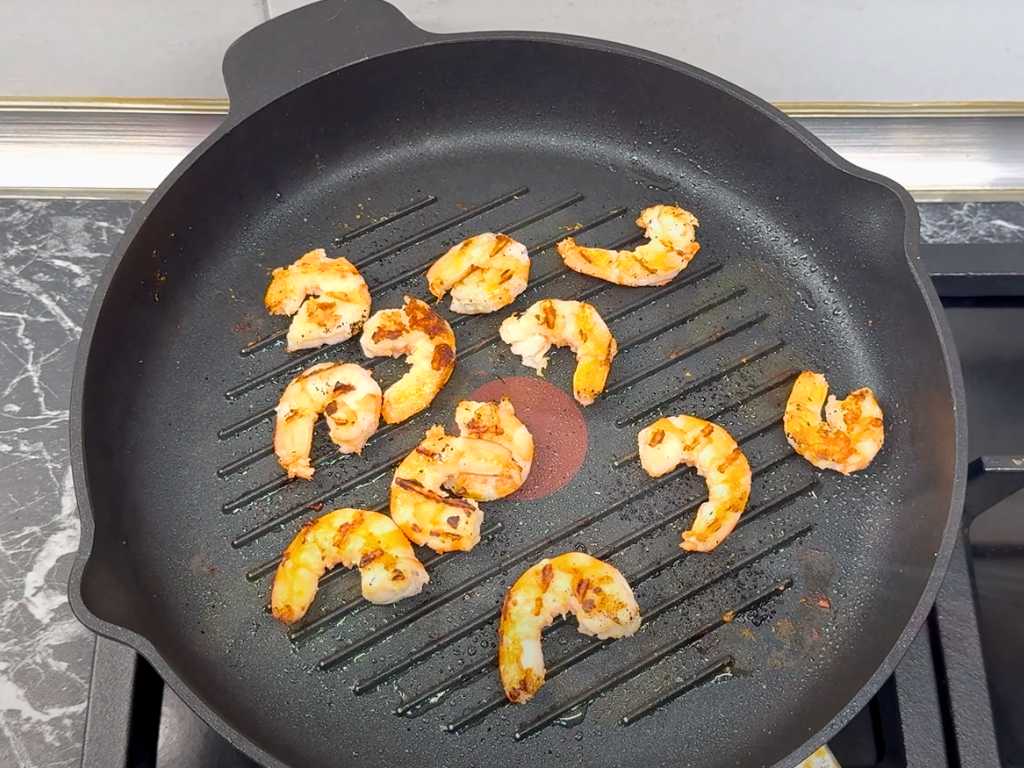 Shrimps cooking in a grill pan until golden and opaque for sweet and savory shrimp salad.