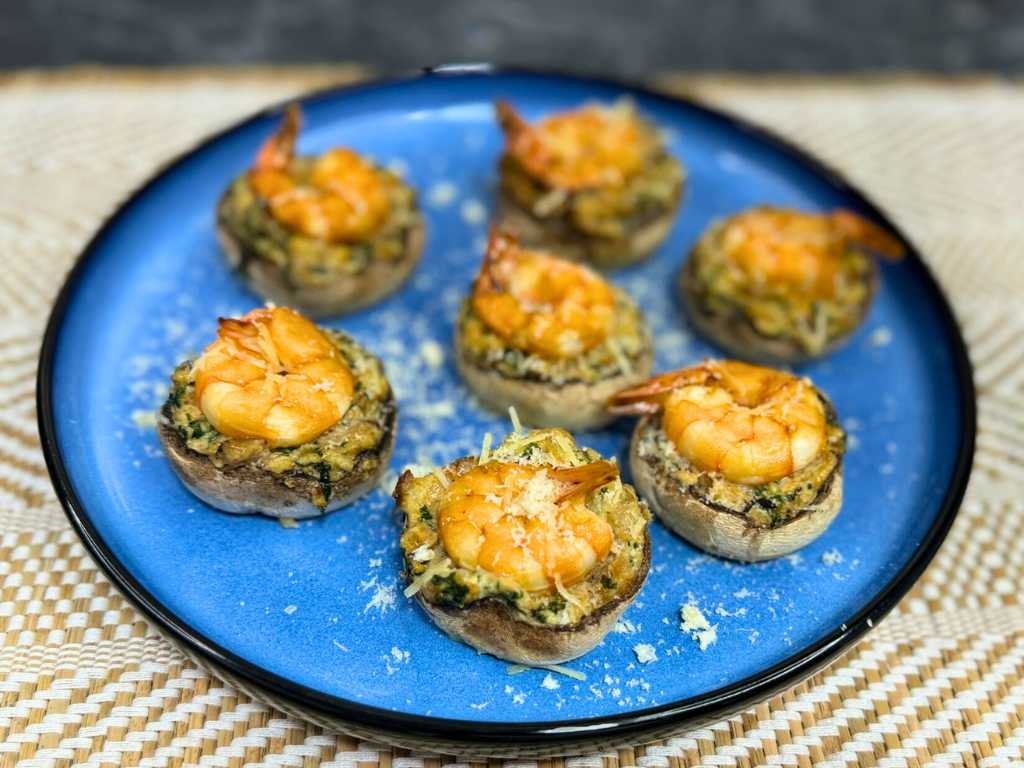 Baked shrimp stuffed mushrooms with creamy spinach filling and golden parmesan topping on a blue plate
