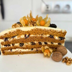 Layered honey bun cake with creamy filling, dried plums, walnuts, and decorative topping – Russian honey cake recipe
