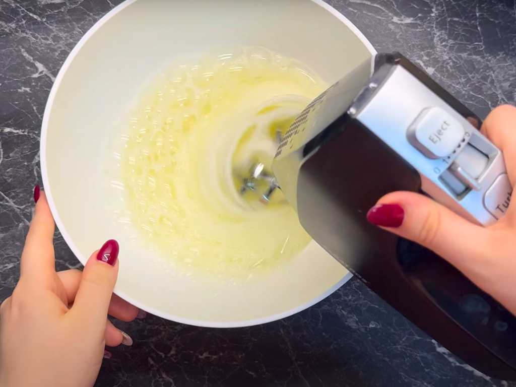 Beating egg whites with an electric mixer until stiff peaks form, an essential step for making light and fluffy pancakes.