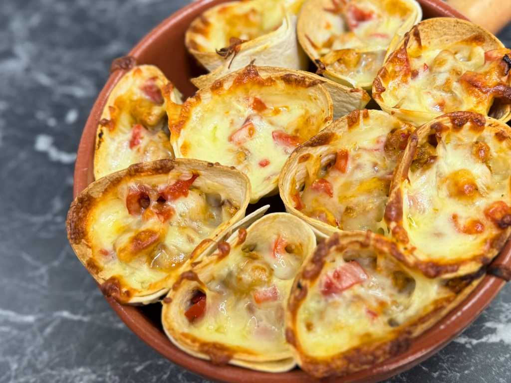 Freshly baked cheesy chicken quesadilla cones in a dish, filled with vegetables and melted cheese