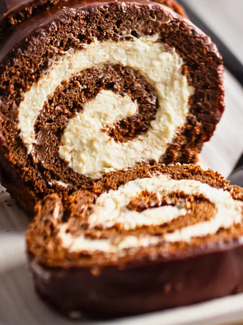 Easy no-bake coconut dessert roll with creamy coconut filling and chocolate biscuit dough, sliced into swirls