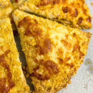 Crispy baked chicken tortilla wraps coated in cornflakes and melted cheese, golden brown and oven-fresh on a baking tray.