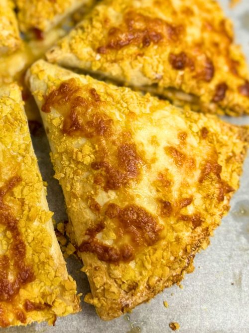 Crispy baked chicken tortilla wraps coated in cornflakes and melted cheese, golden brown and oven-fresh on a baking tray.