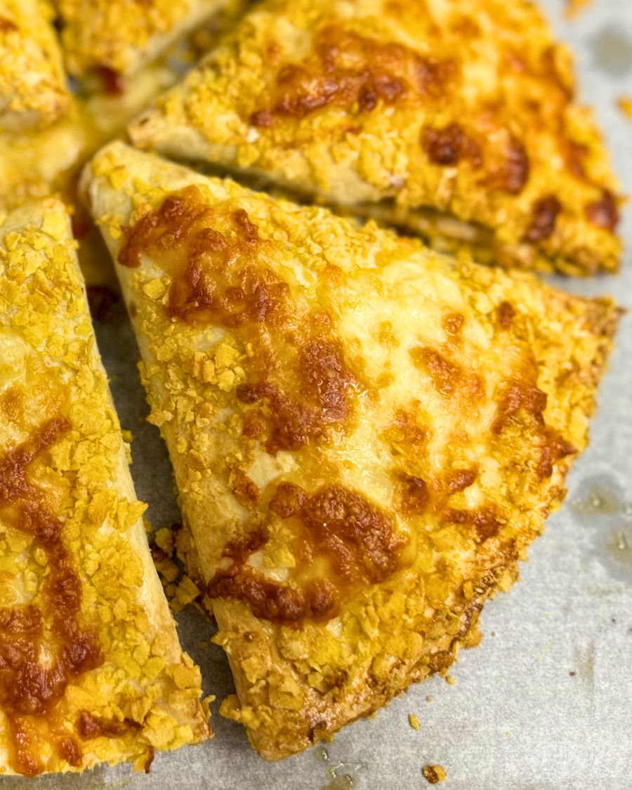 Crispy baked chicken tortilla wraps coated in cornflakes and melted cheese, golden brown and oven-fresh on a baking tray.