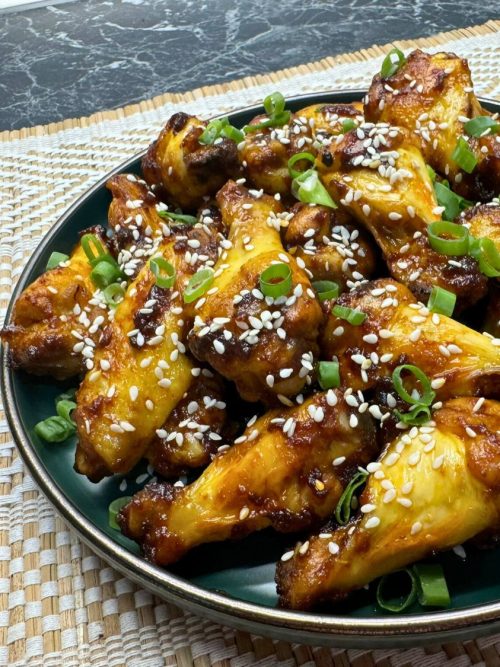 Plate of honey soy chicken wings topped with sesame seeds and sliced green onions