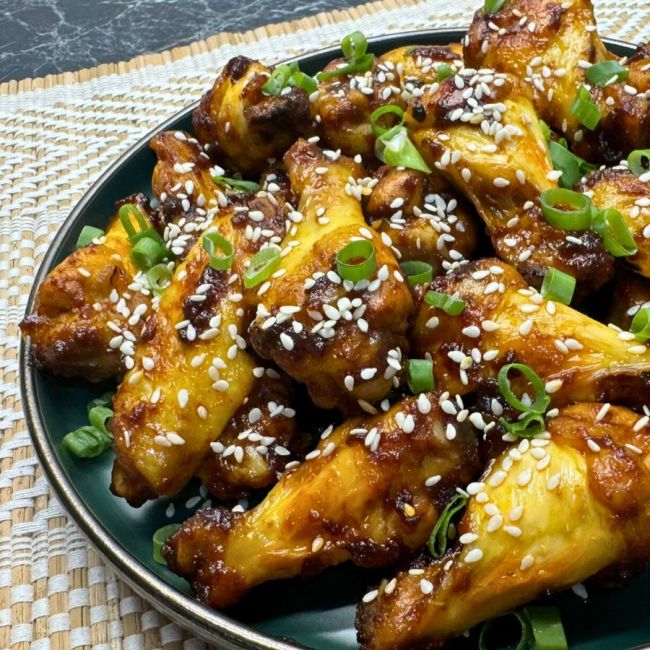 Plate of honey soy chicken wings topped with sesame seeds and sliced green onions