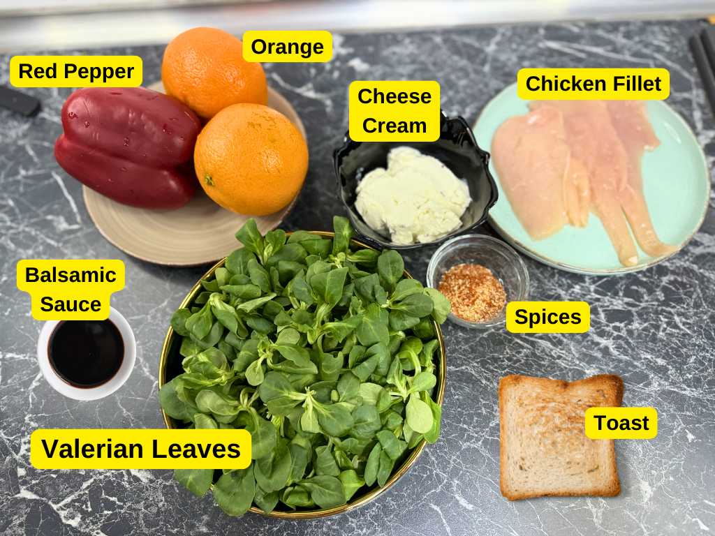 Ingredients for healthy summer chicken salad including chicken fillet, red pepper, oranges, feta or cream cheese, valerian leaves, balsamic sauce, spices, and toast