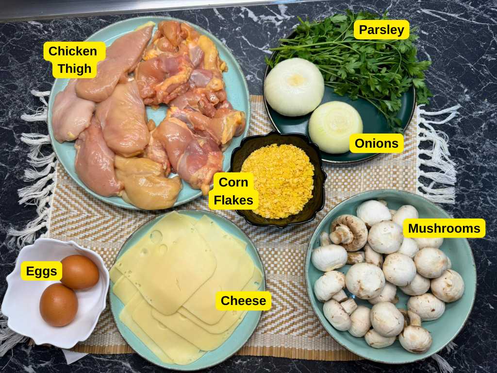 Ingredients for baked chicken pockets recipe – chicken thighs, mushrooms, onions, parsley, cheese, eggs, and cornflakes on a kitchen counter