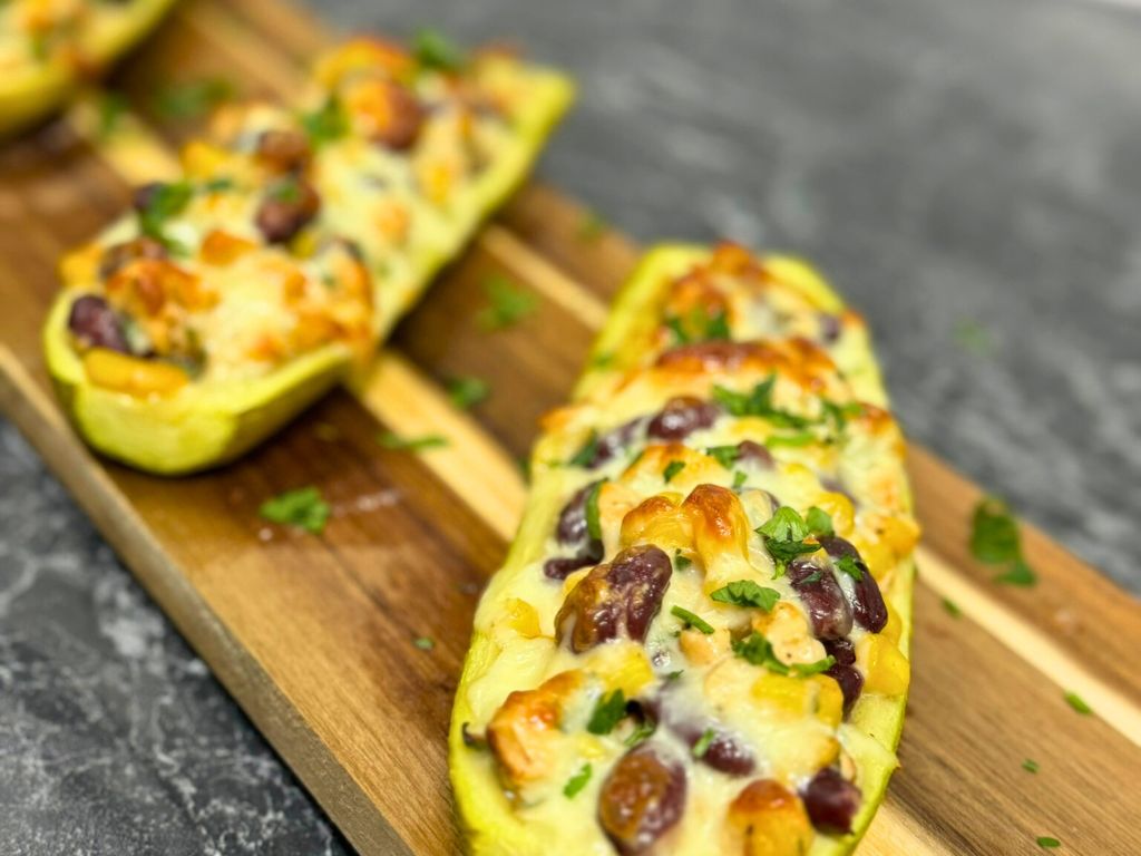 Close-up of baked stuffed zucchini boats with chicken, beans, corn, and melted cheese – recipe stuffed zucchini boats
