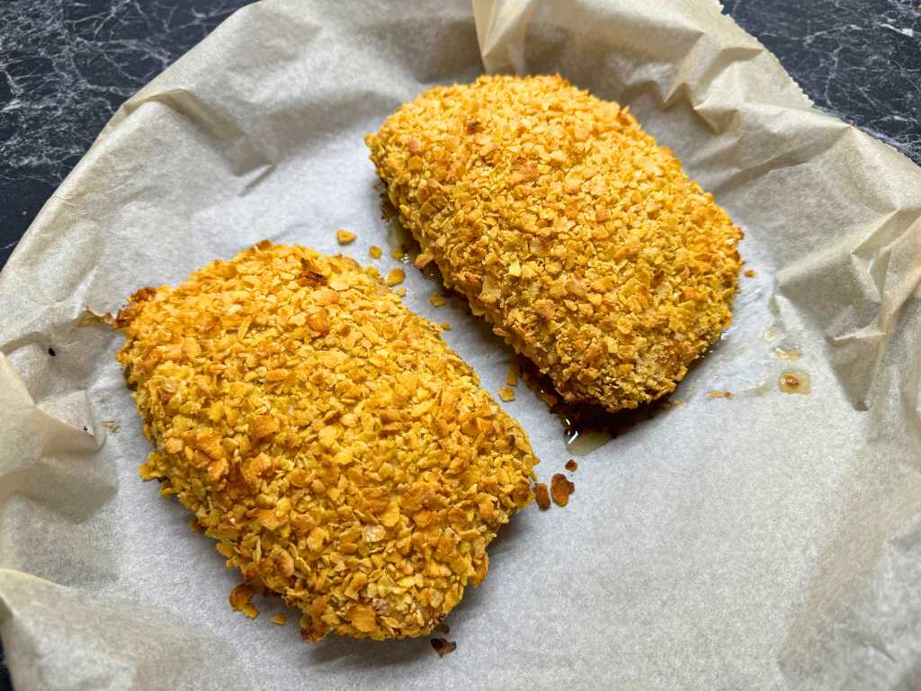 Freshly baked chicken pockets with crispy golden cornflake crust on a parchment-lined tray