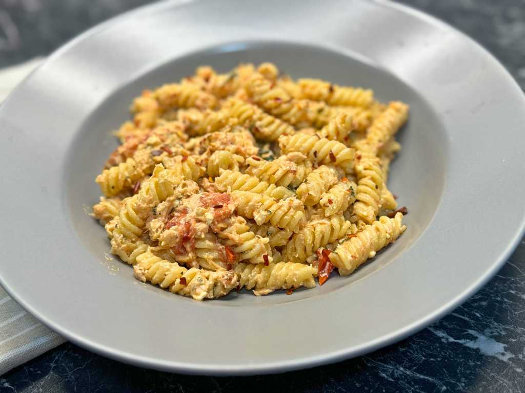 Creamy salmon pasta with feta, spinach, and cherry tomatoes served on a plate