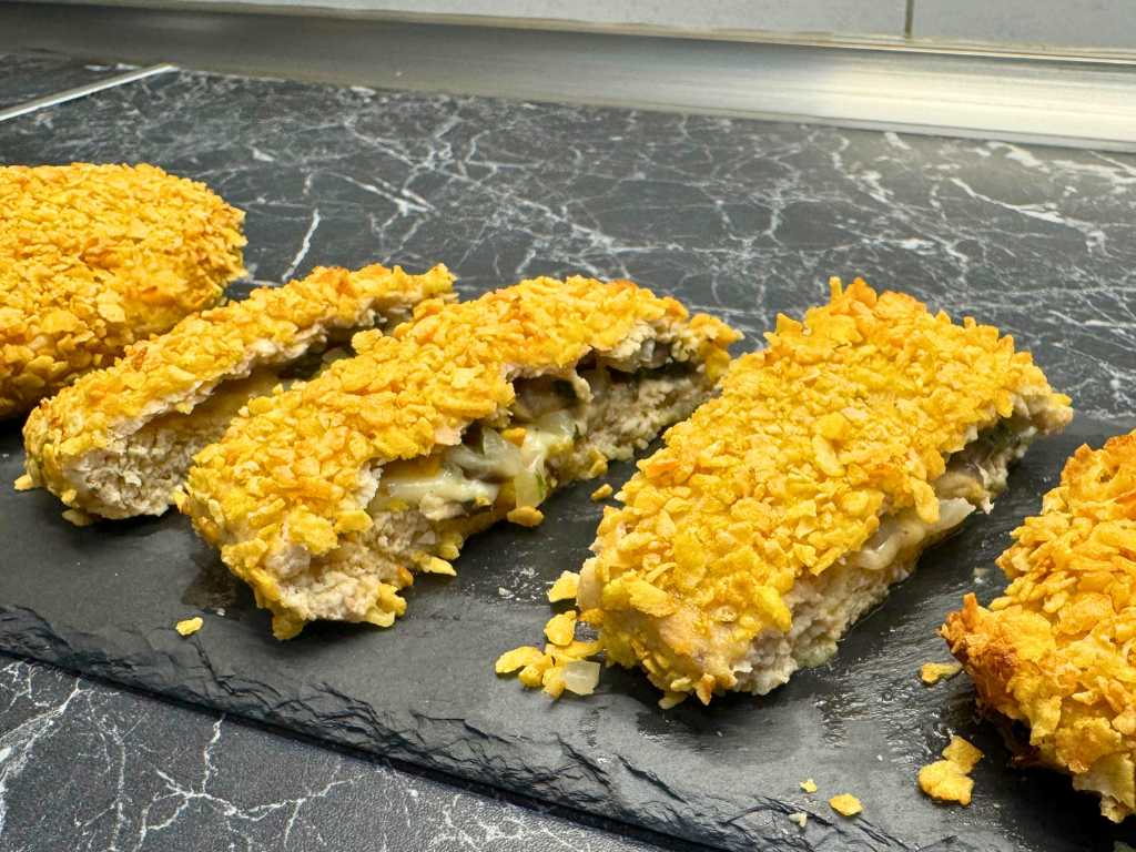 Sliced baked chicken pockets showing crispy cornflake crust with melted cheese and mushroom filling inside