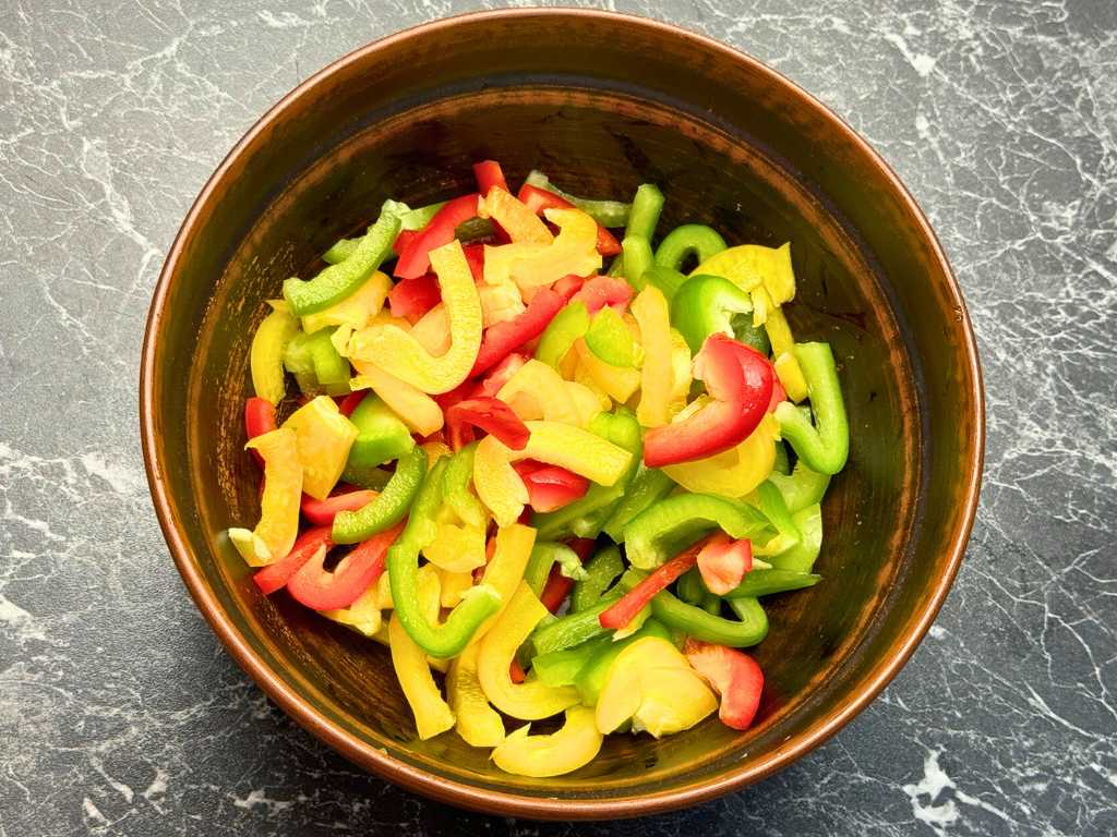 Bowl of freshly sliced red, green, and yellow bell peppers for Tbilisi Salad.