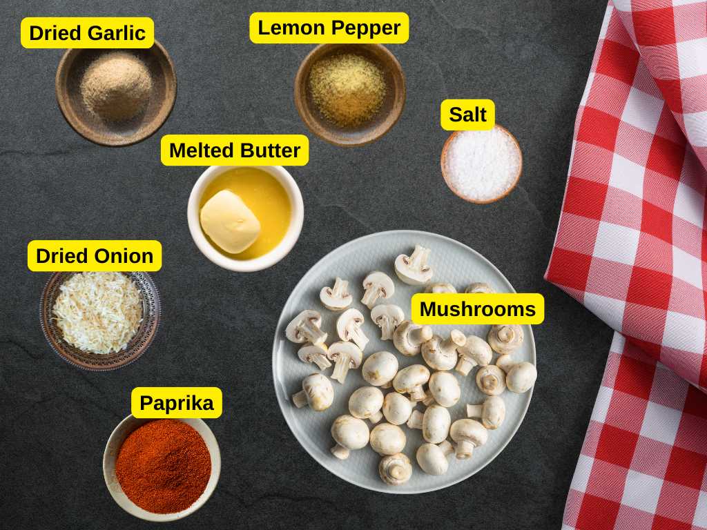 Overhead view of mushrooms, melted butter, paprika, lemon pepper, dried garlic, dried onion, and salt on a dark surface with a red checkered cloth.