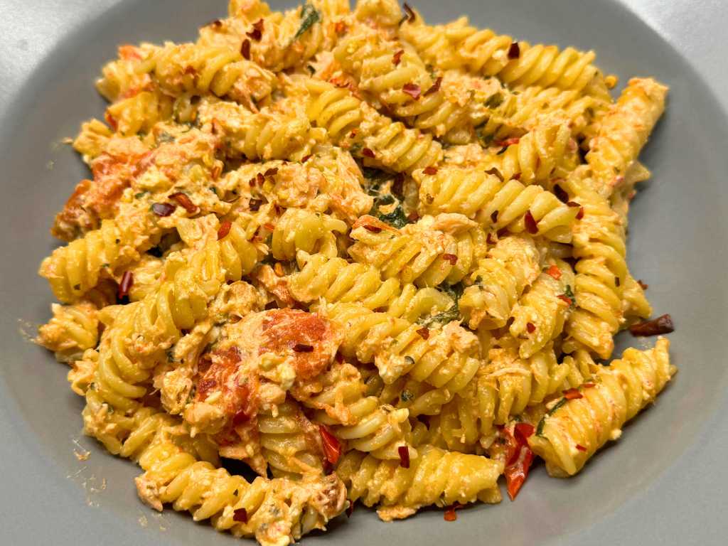 Close-up of creamy salmon pasta with feta, spinach, and roasted cherry tomatoes