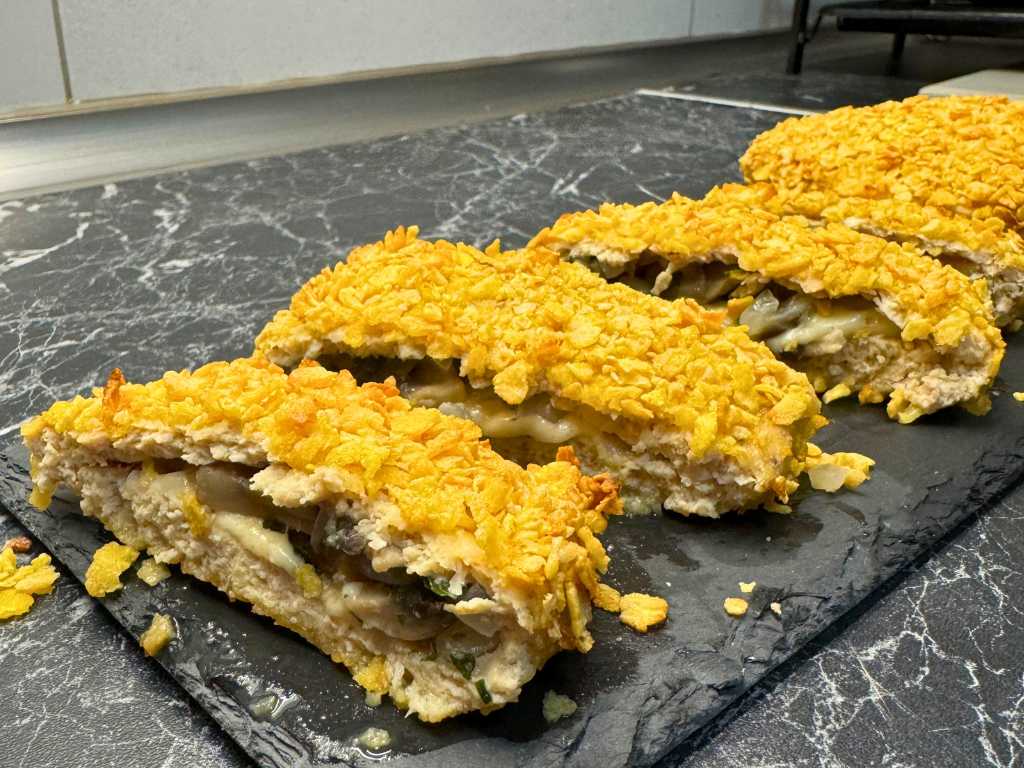 Sliced baked chicken pockets showing crispy cornflake crust with melted cheese and mushroom filling inside