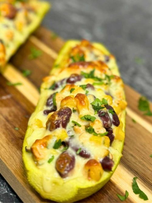 Close-up of baked stuffed zucchini boat with chicken, beans, corn, and melted cheese – recipe stuffed zucchini boats