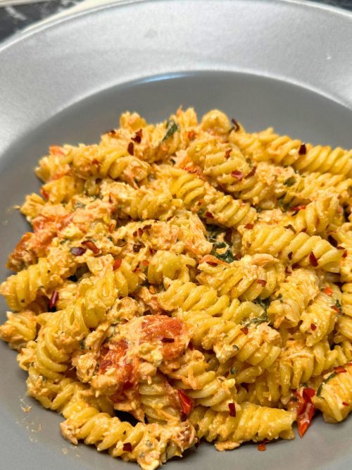 Creamy salmon pasta with feta, spinach, and cherry tomatoes served on a plate