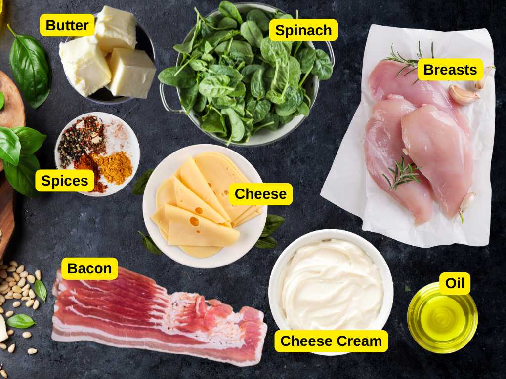 Flat lay of ingredients for bacon-wrapped chicken rolls, including chicken breasts, spinach, cream cheese, sliced cheese, bacon, butter, oil, and spices.