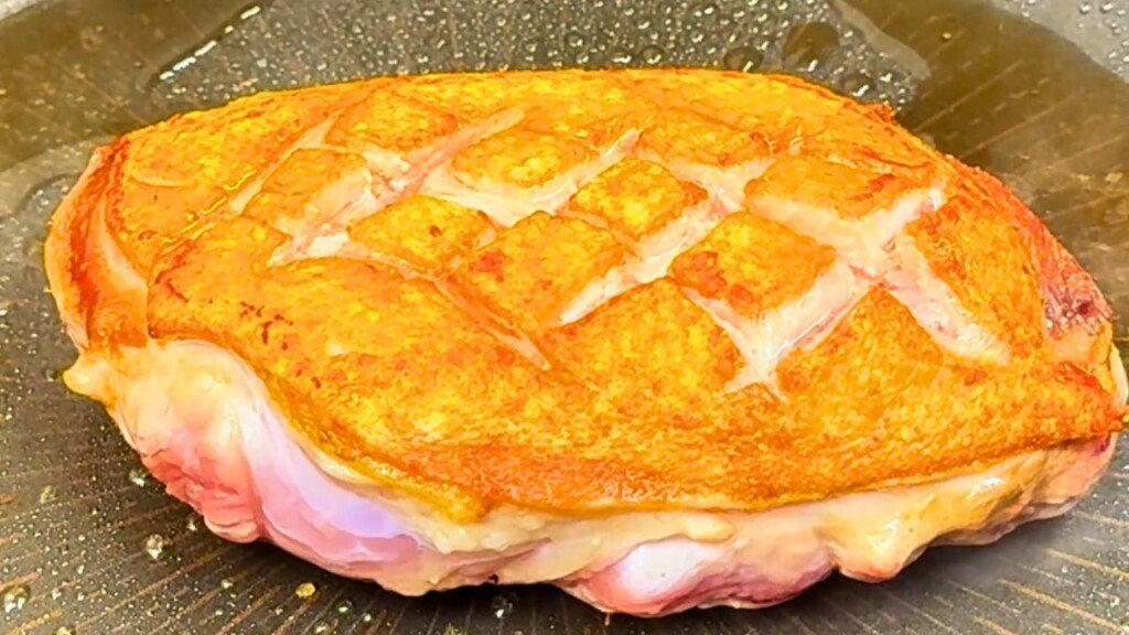 Golden brown duck breast seared skin-side down in a hot pan, showing crispy crosshatched skin and rendered fat—perfect for a honey orange glaze.