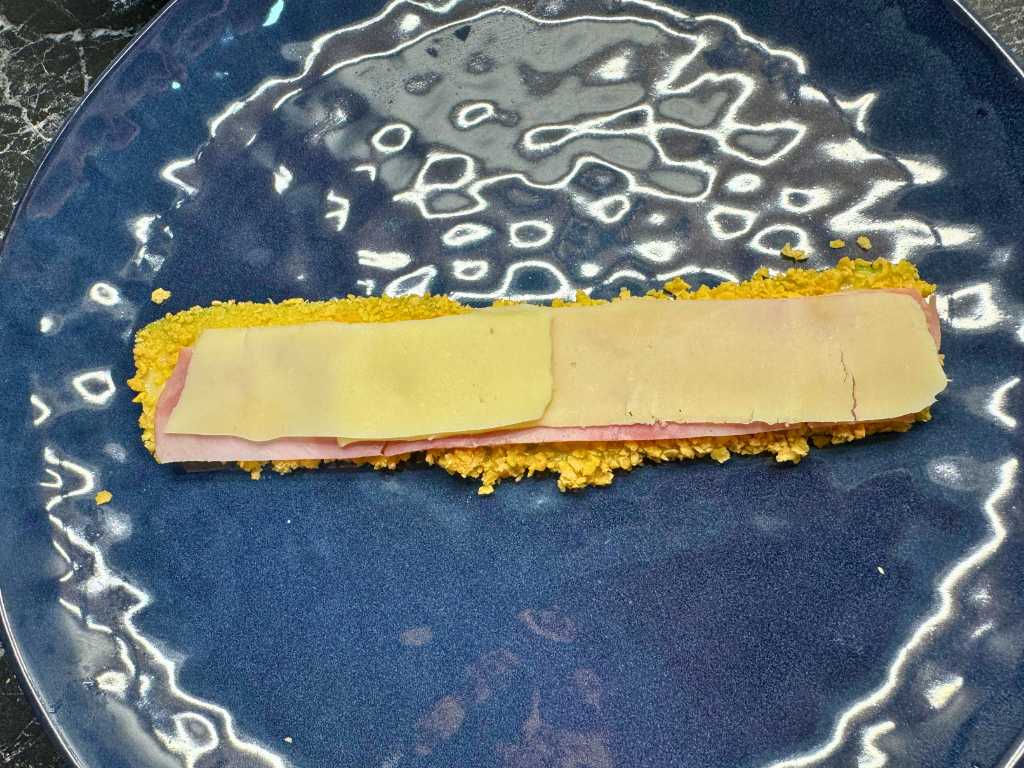 Breaded zucchini slice layered with ham and cheese before adding mashed potato filling for roll skewers