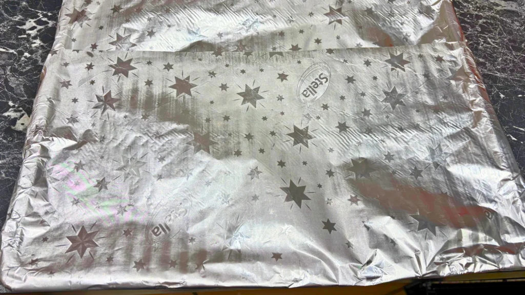 A sheet of star-patterned aluminum foil prepared for covering pork ribs before baking.
