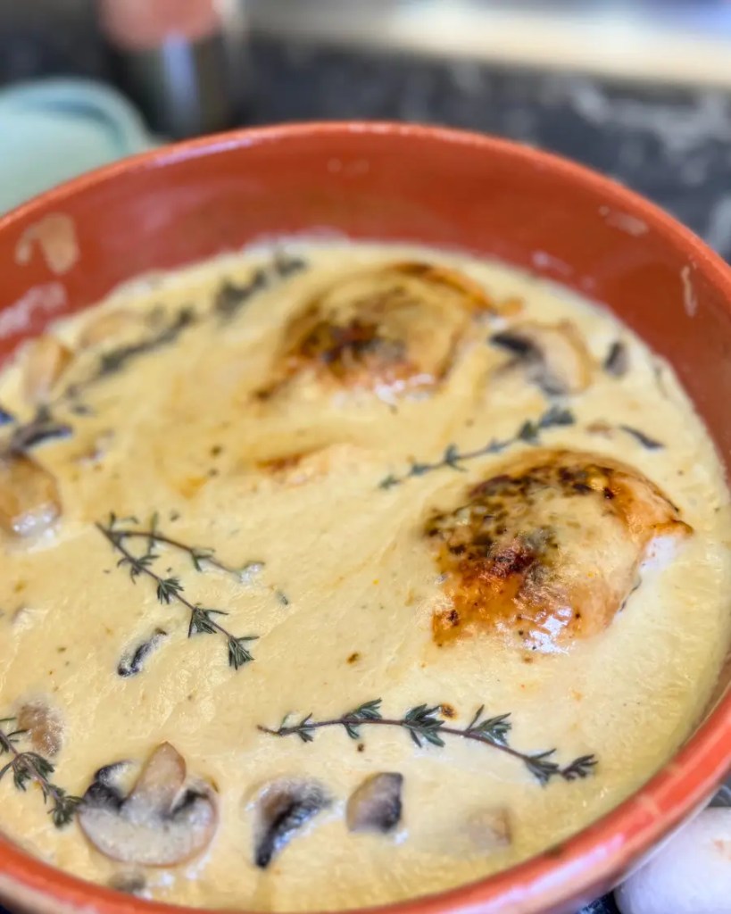 juicy baked chicken breast in creamy mushroom sauce garnished with thyme