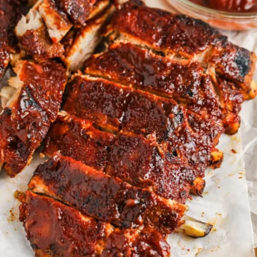 Sliced pork ribs with a glossy reddish-brown glaze resting on parchment paper.