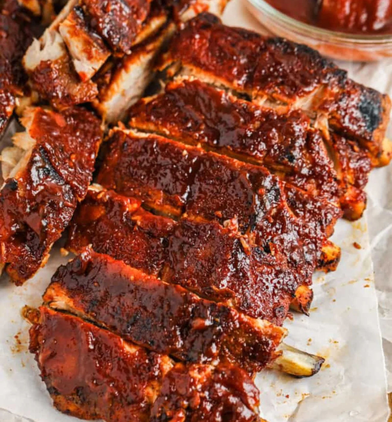 Sliced pork ribs with a glossy reddish-brown glaze resting on parchment paper.