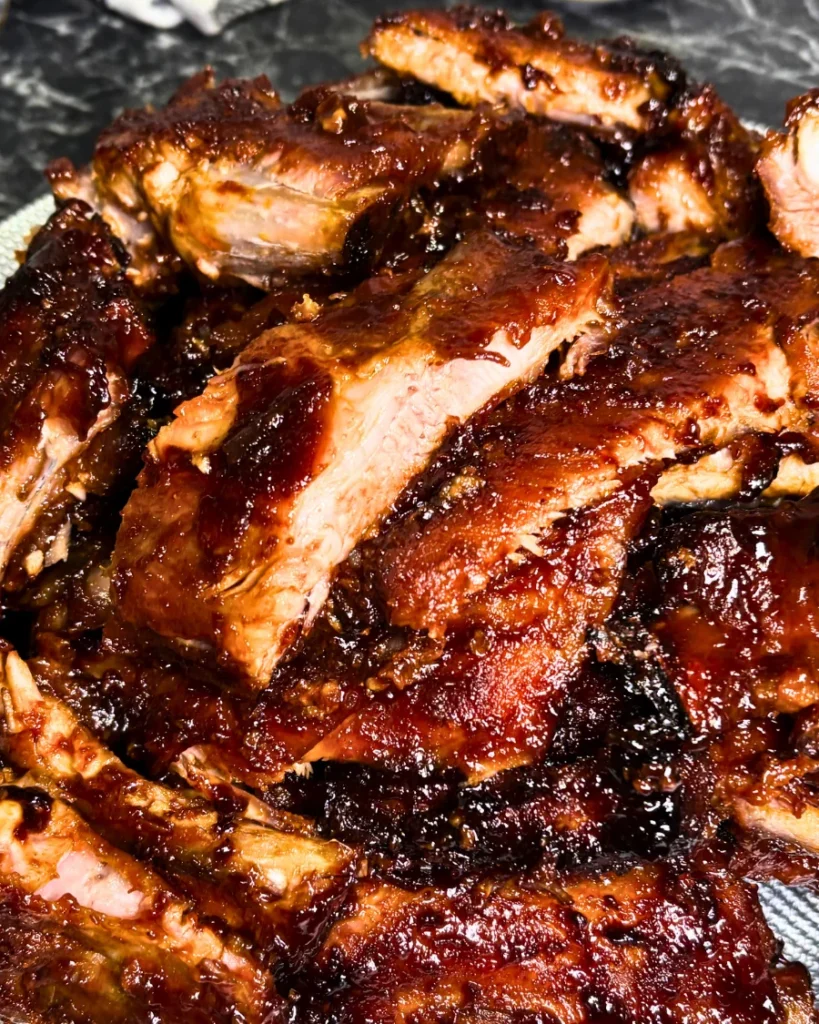 Close-up of oven-baked pork ribs coated in a glossy, dark sauce.