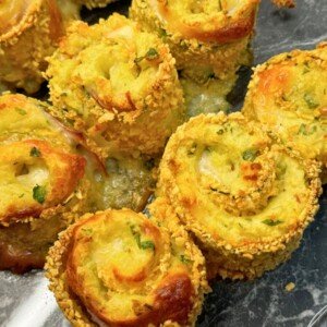 Crispy baked zucchini roll skewers filled with mashed potatoes, cheese, ham, and bacon, coated in golden panko crumbs and garnished with parsley