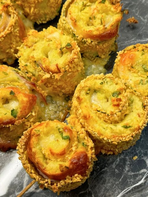 Crispy baked zucchini roll skewers filled with mashed potatoes, cheese, ham, and bacon, coated in golden panko crumbs and garnished with parsley