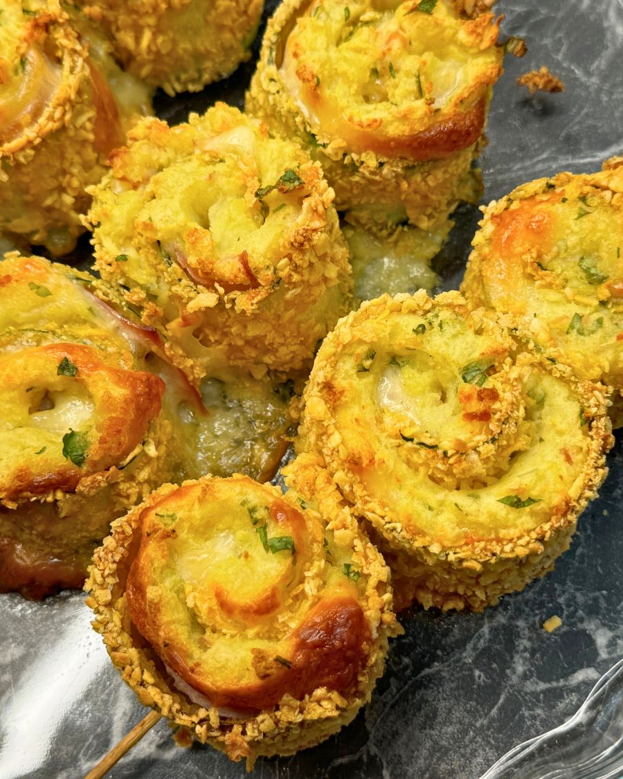 Crispy baked zucchini roll skewers filled with mashed potatoes, cheese, ham, and bacon, coated in golden panko crumbs and garnished with parsley