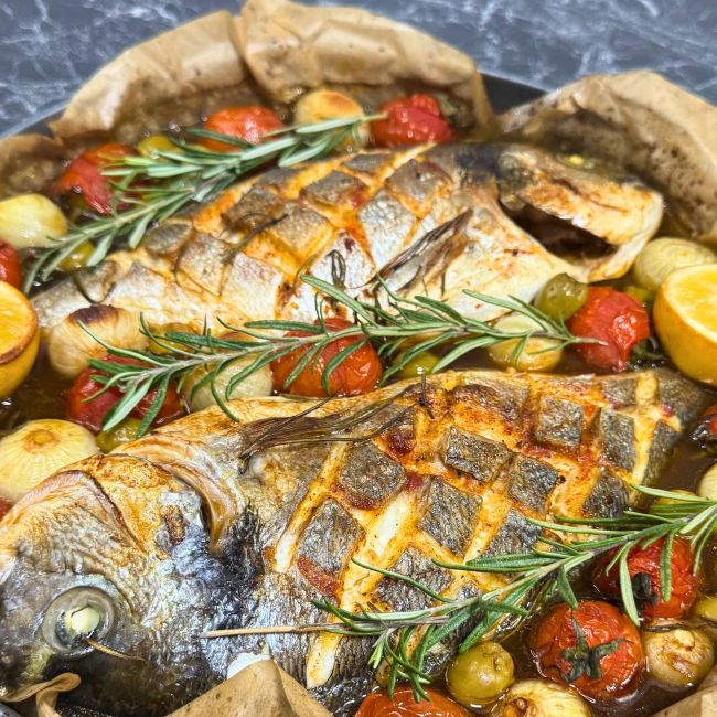 Two whole dorada fish baked with dark beer, cherry tomatoes, onions, olives, lemon, and fresh rosemary in a one-pot Mediterranean dish.