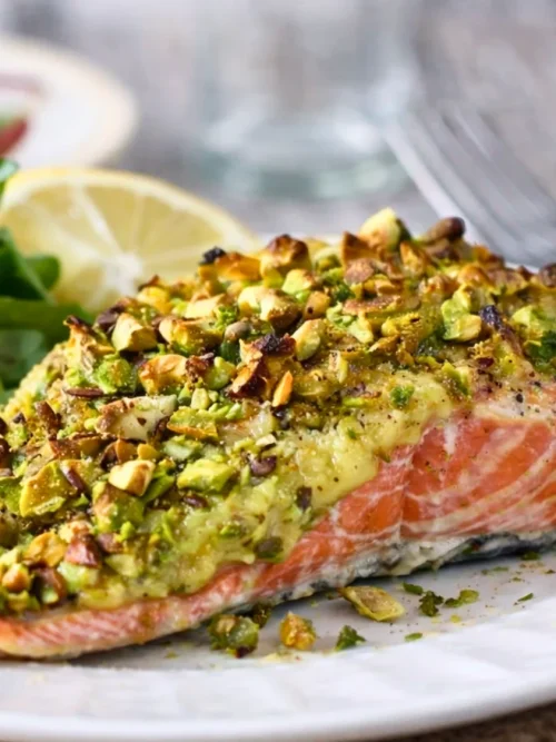 Oven baked salmon with avocado cream and chopped pistachios, served with fresh green salad