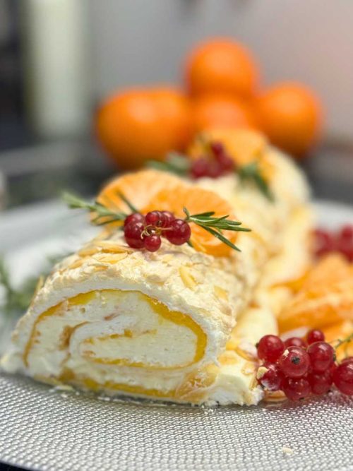 Slice of mandarin meringue roll with creamy filling and citrus curd