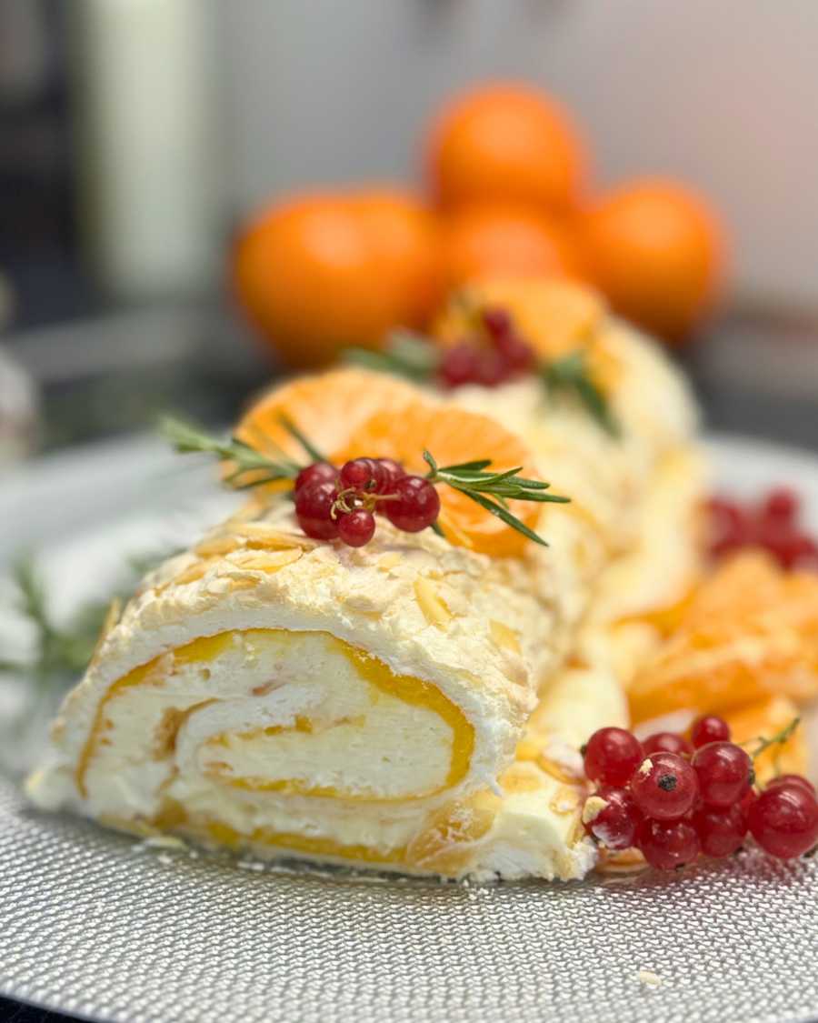 Slice of mandarin meringue roll with creamy filling and citrus curd