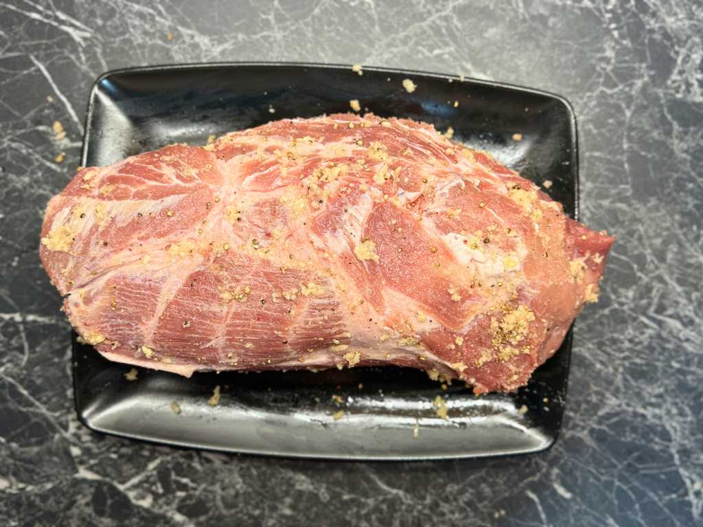 Raw pork neck rubbed with garlic, salt, and black pepper before marinating