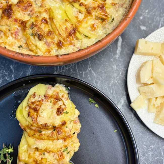 Creamy au gratin potatoes made with thinly sliced yellow potatoes, bacon, roasted garlic, heavy cream, and a blend of Gruyere, classic cheese, and Parmesan, baked until golden and bubbly