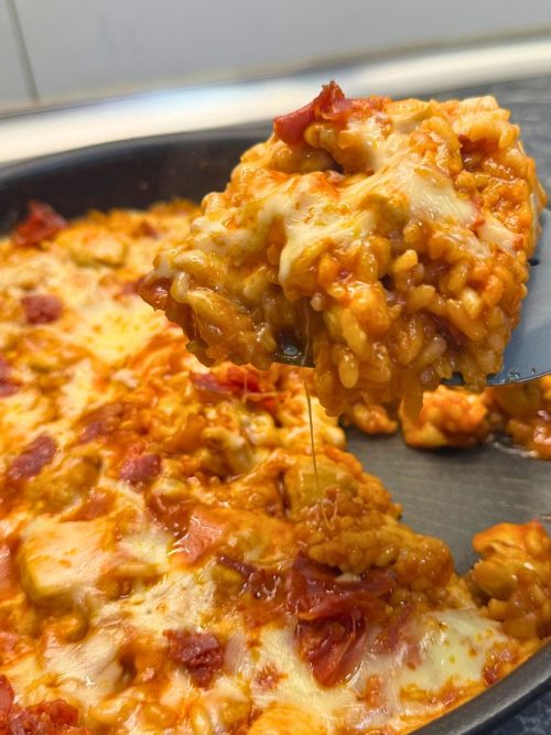 One pan chicken and chorizo rice topped with melted cheese, being scooped from the pan.