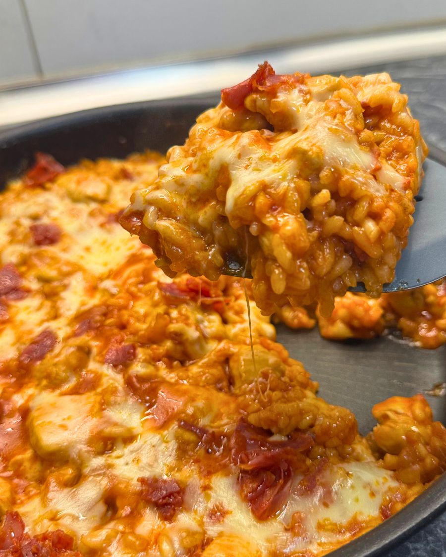One pan chicken and chorizo rice topped with melted cheese, being scooped from the pan.