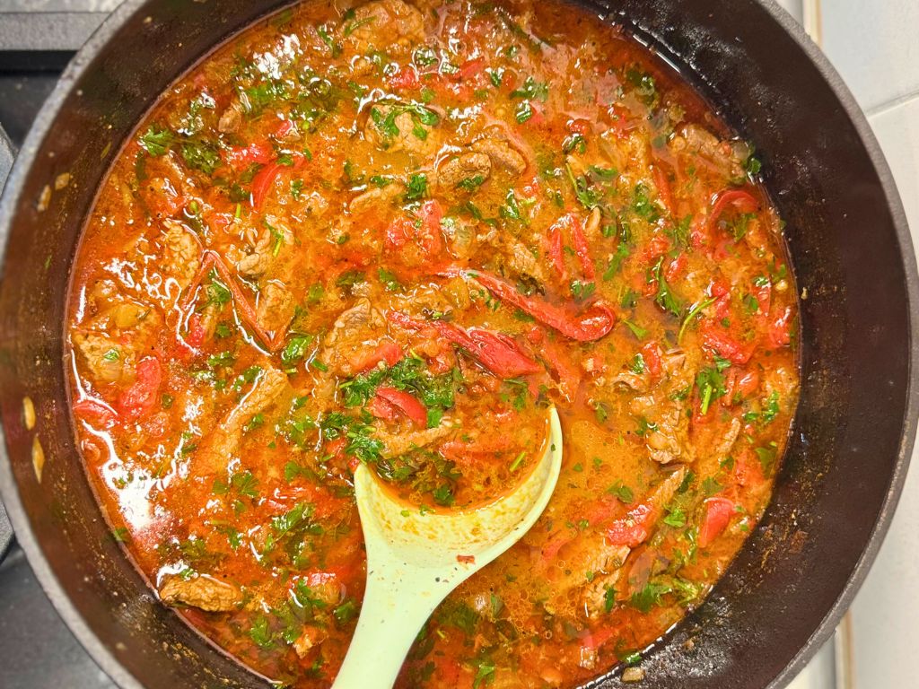A front shot of a pot full of Tender Skillet Beef Stew and a mixing spoon