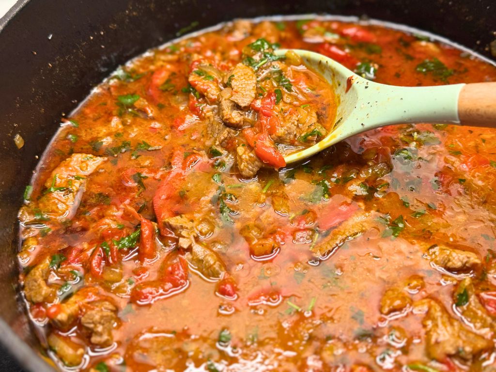 A side shot of a pot of Tender Skillet Beef Stew and a spoon in it.