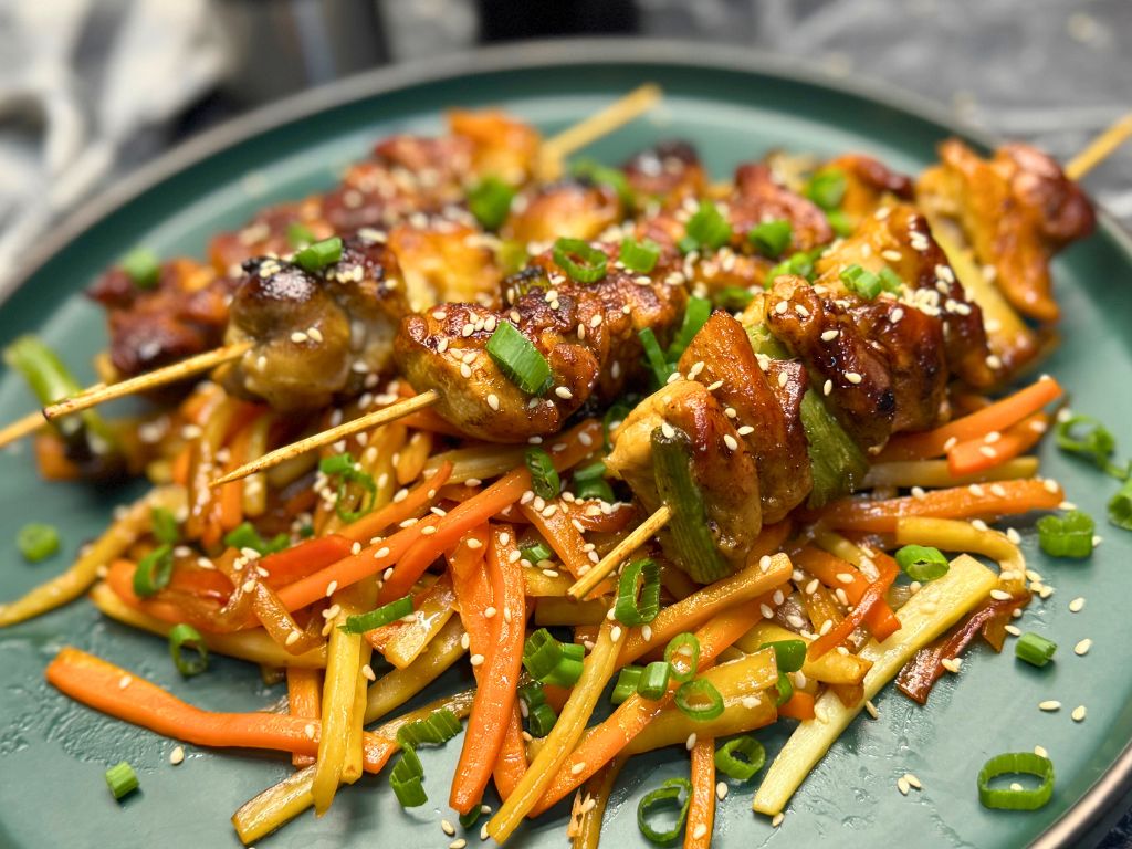 Several pieces of Teriyaki Chicken Skewers on a green plate.