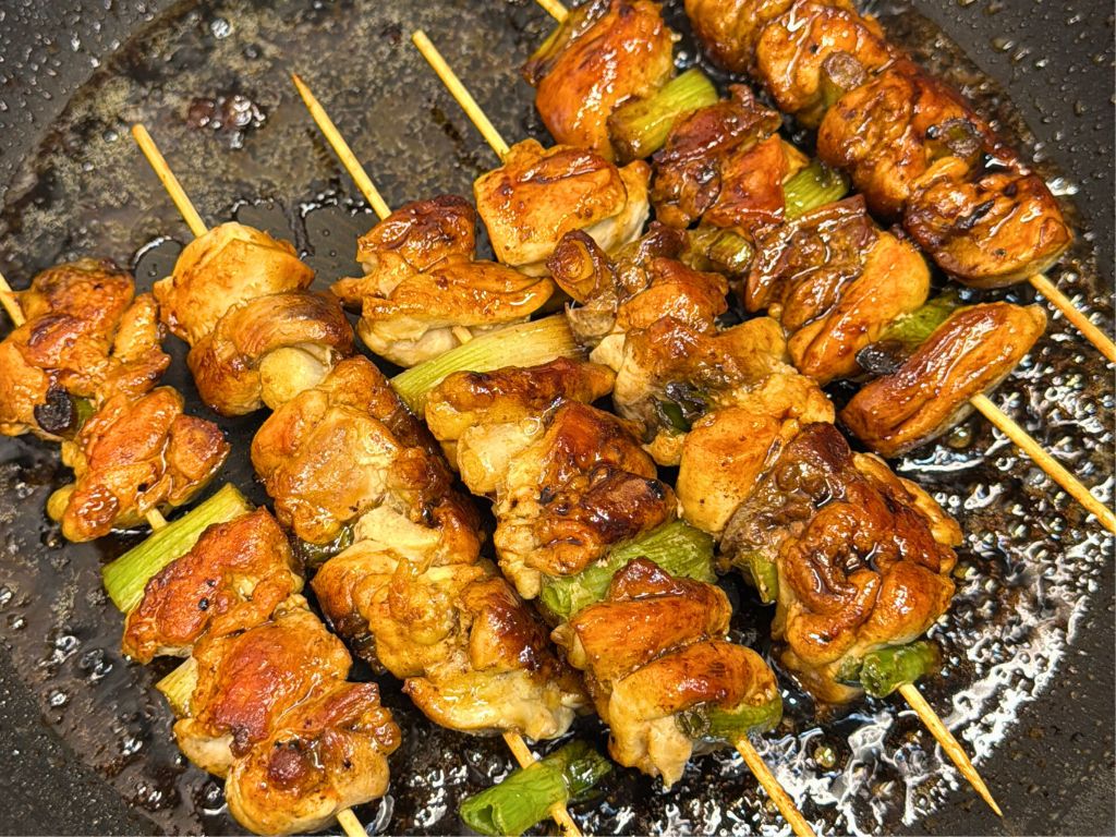 Several sticks of Teriyaki Chicken Skewers in a pan.