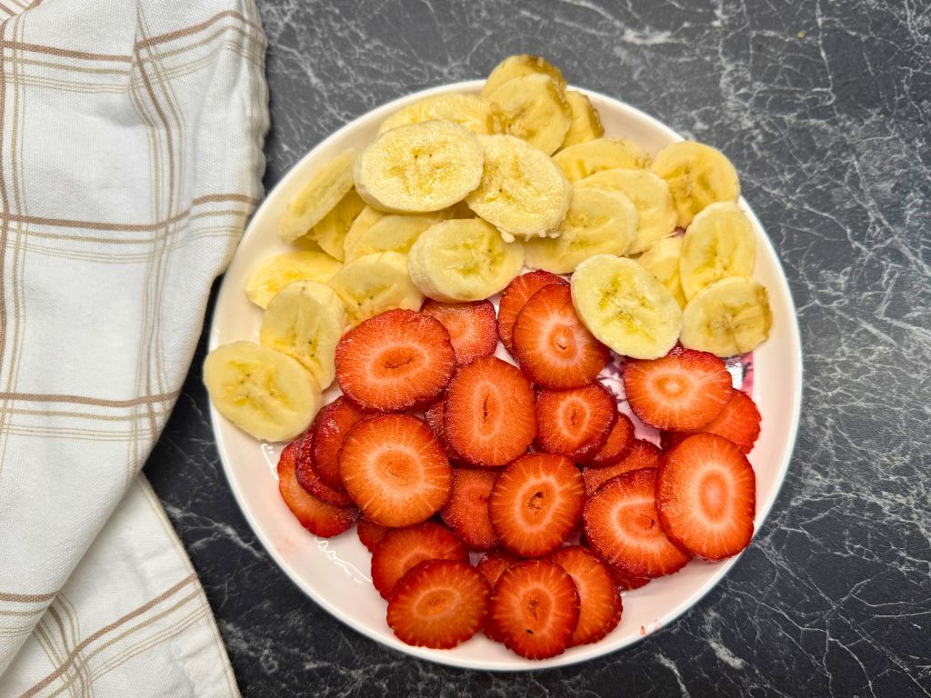 A plate of strawberries and round-slices bananas.